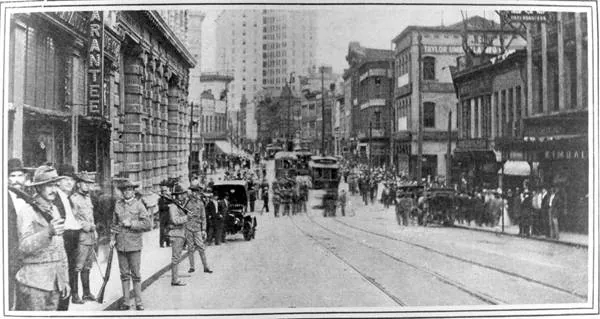 State militia soldiers standing in Peachtree Street just south of Five Points in 1906, a streetcar and onlookers behind them.