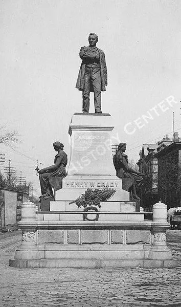 The Henry W. Grady monument in 1895: a bronze figure on a tall stone pedestal with two seated figures at its base.