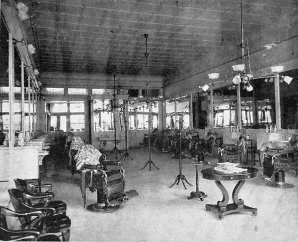 The interior of Herndon’s barbershop in 1903: a long room of mirrors, marble counters, chandeliers and rows of barber chairs.