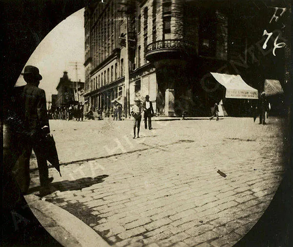 A round-framed photograph of the Kimball House seen along Wall Street, a man on the paved street in the foreground.