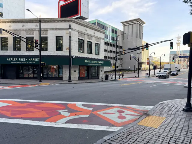The corner grocery at Five Points, the painted street in the foreground.