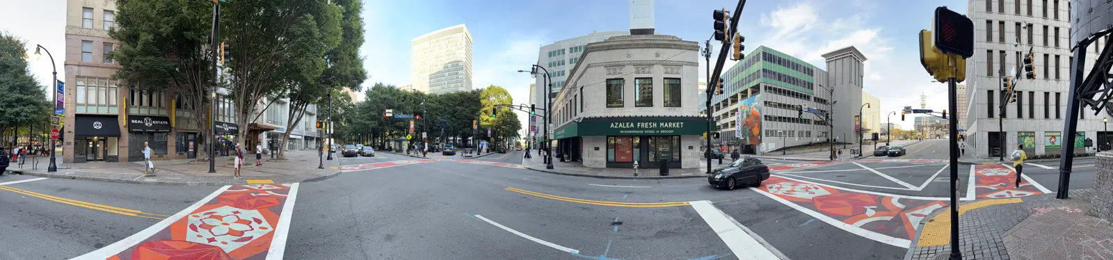 A wide view of the Five Points intersection, the painted crossing, the corner grocery and the office towers.