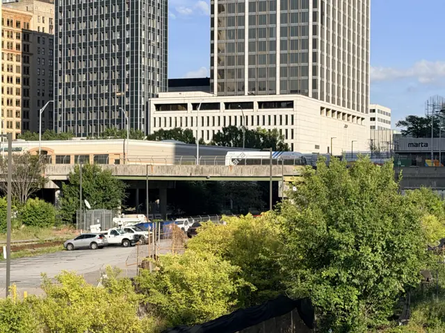 The view east from Forsyth Street over the railroad gulch today: trees, tracks and the Five Points station beyond.