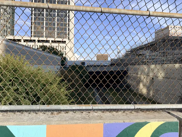 The chain-link fence and mural along the parking lot at 10 Forsyth Street.