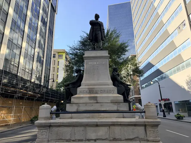 The base of the Grady monument, its stone plinth and the iron fence around it.