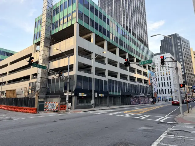 The parking deck from the corner, green glass office floors above it.