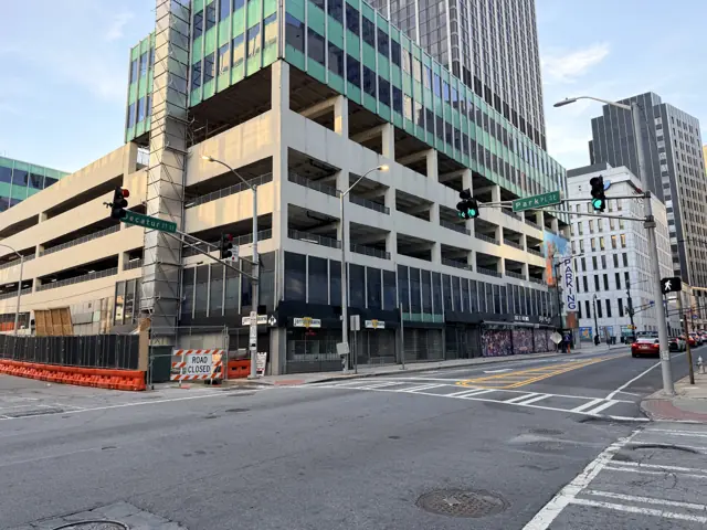 The deck across the intersection, traffic signals and a fenced sidewalk.